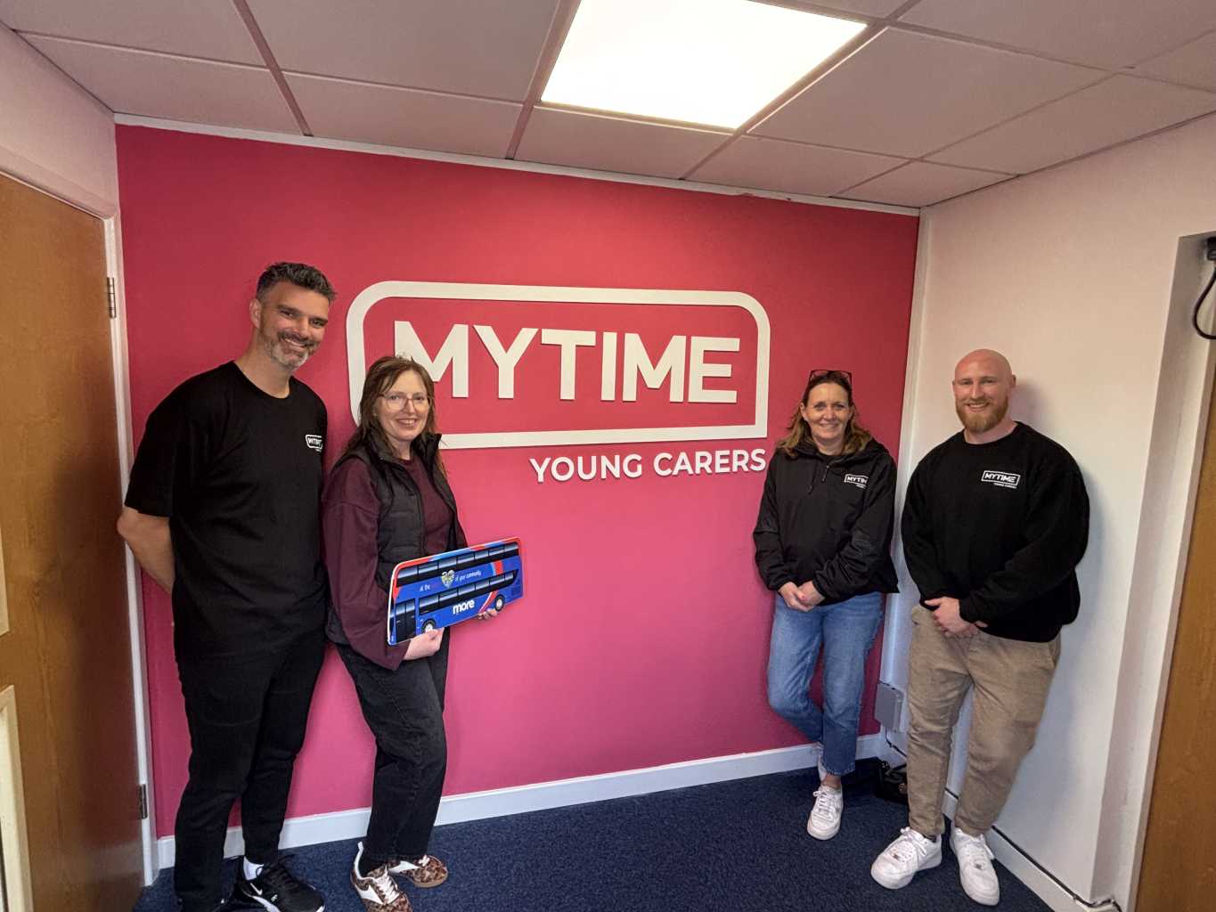 Photo in front of pink MYTIME Young Carers wall