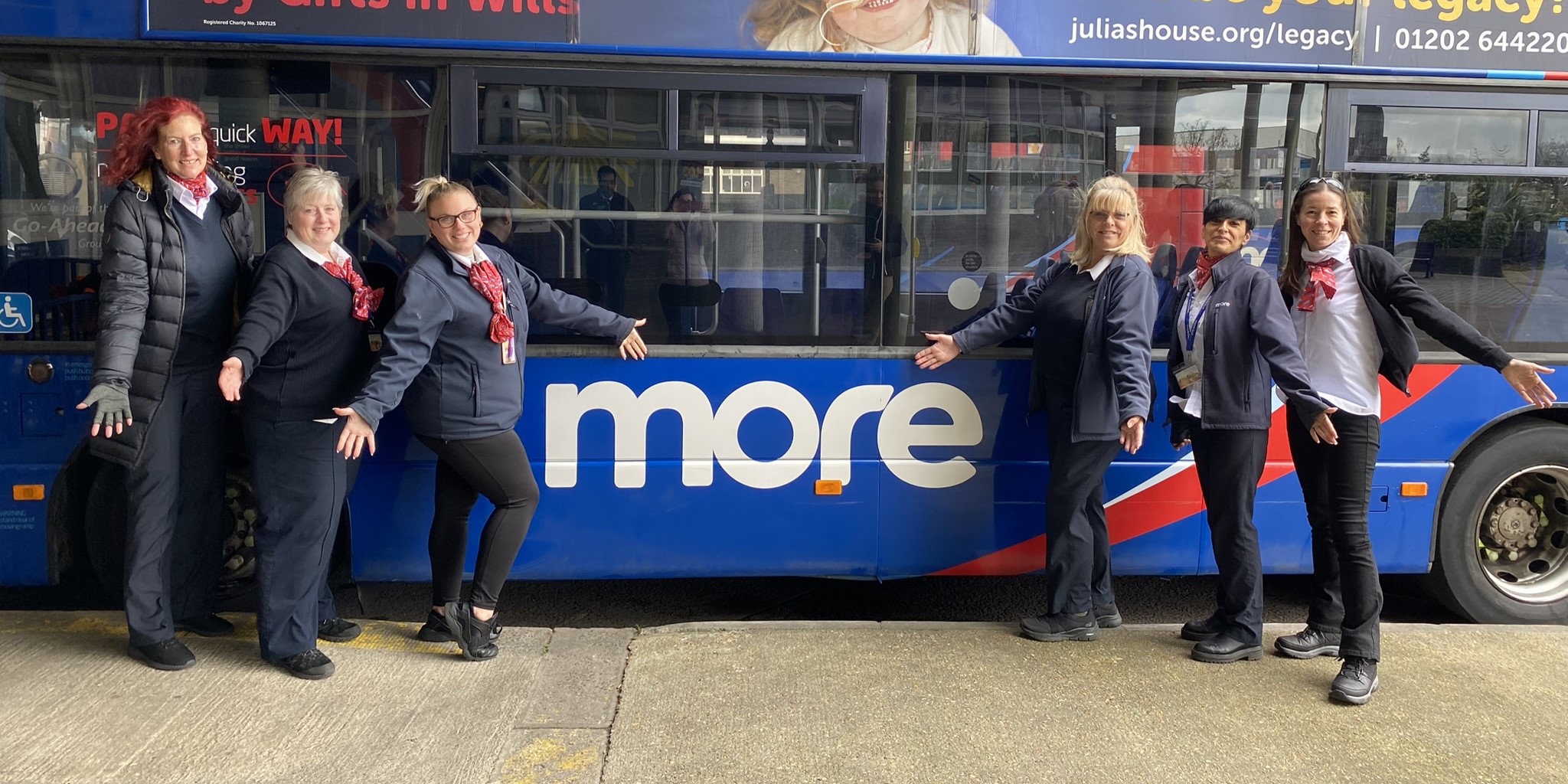 6 lady drivers outside of a more branded bus