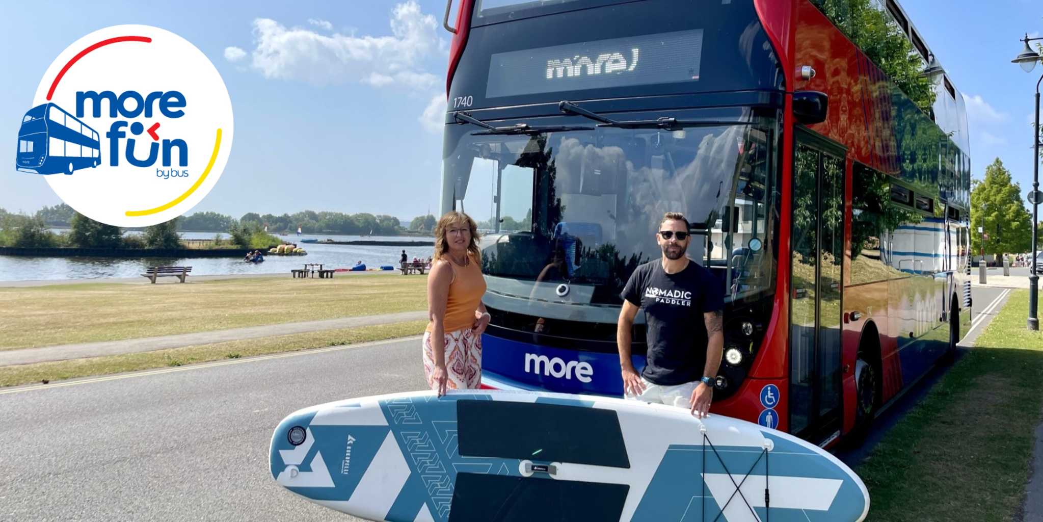 Man and woman in front of a bus with a paddleboard
