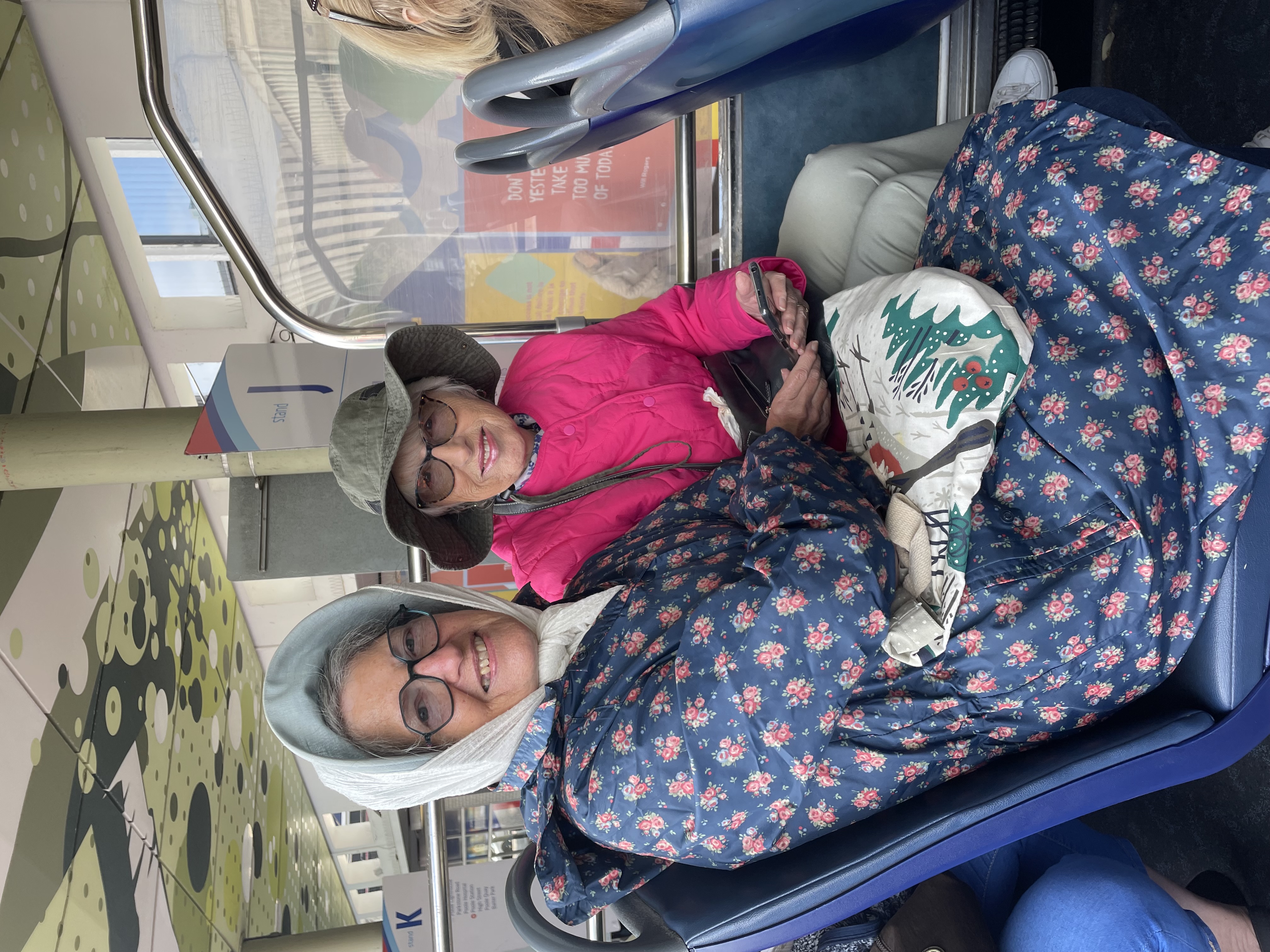two senior ladies wrapped up on open top bus