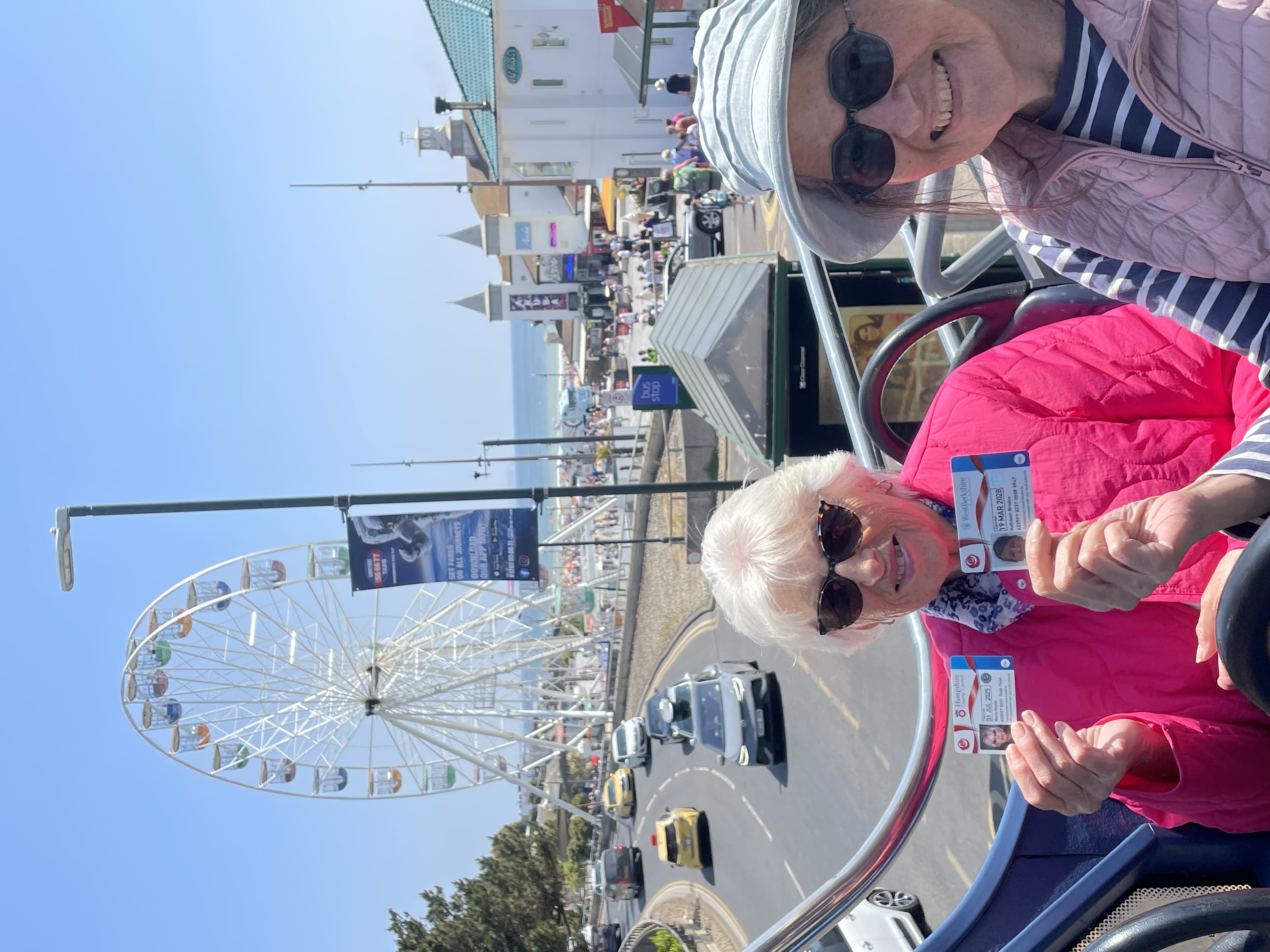 female pensioners holding bus passes on open top bus