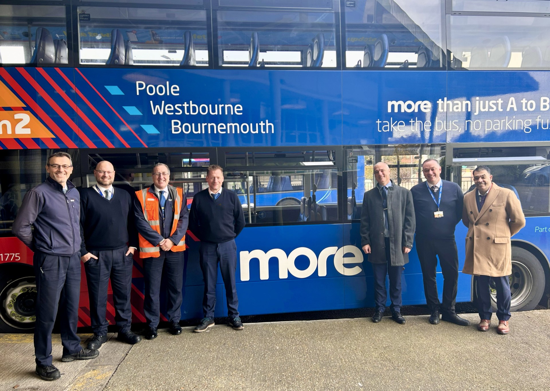 Group of men from morebus stood around a bus